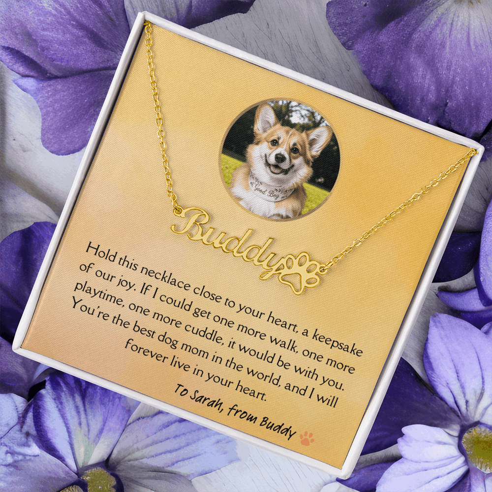 Golden dog remambrance necklace in soft touch gift box with heartfelt light orange message card from beloved pet. Purple flowers in the background.