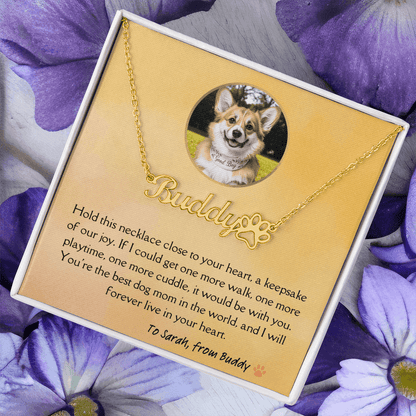 Golden dog remambrance necklace in soft touch gift box with heartfelt light orange message card from beloved pet. Purple flowers in the background.